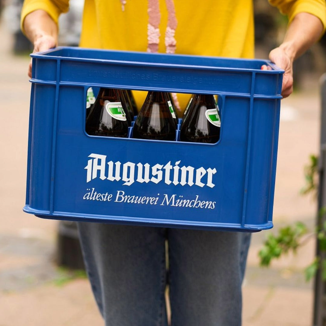 Person holding Augustiner crate with bottles inside